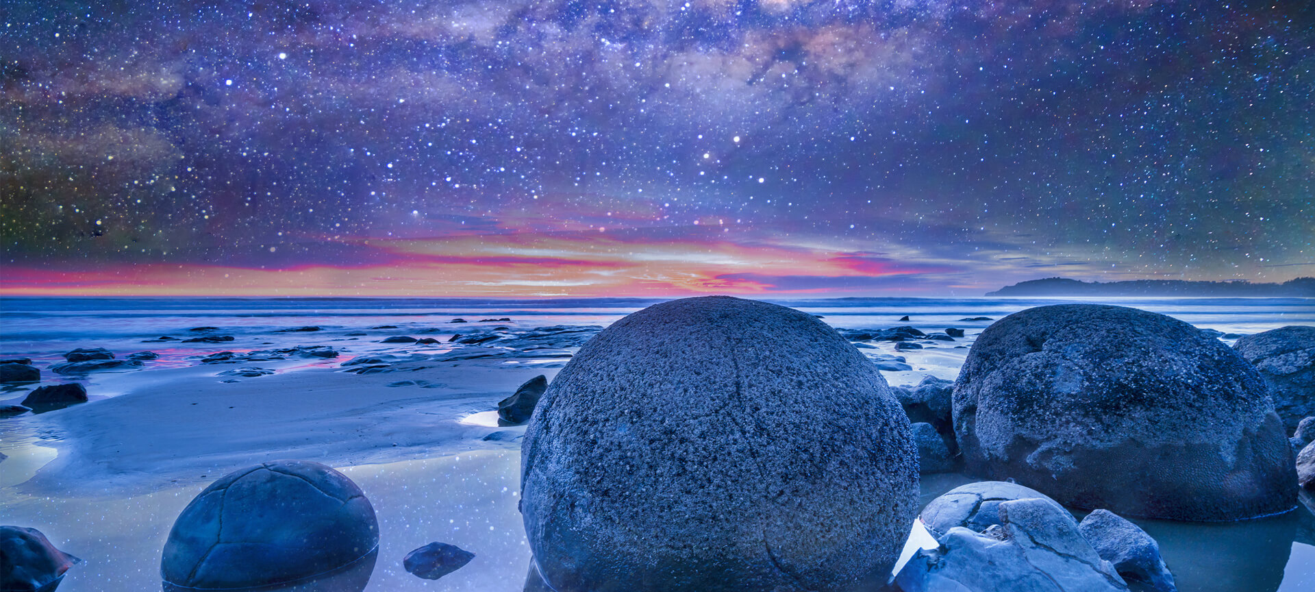 Moeraki boulders looking out to sea with starry night sky and sunset